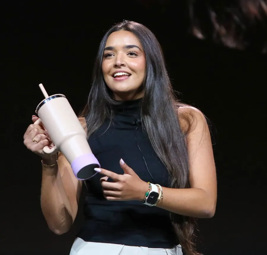 Rima, co-founder of syp, on stage holding a tumbler with the syp sleeve